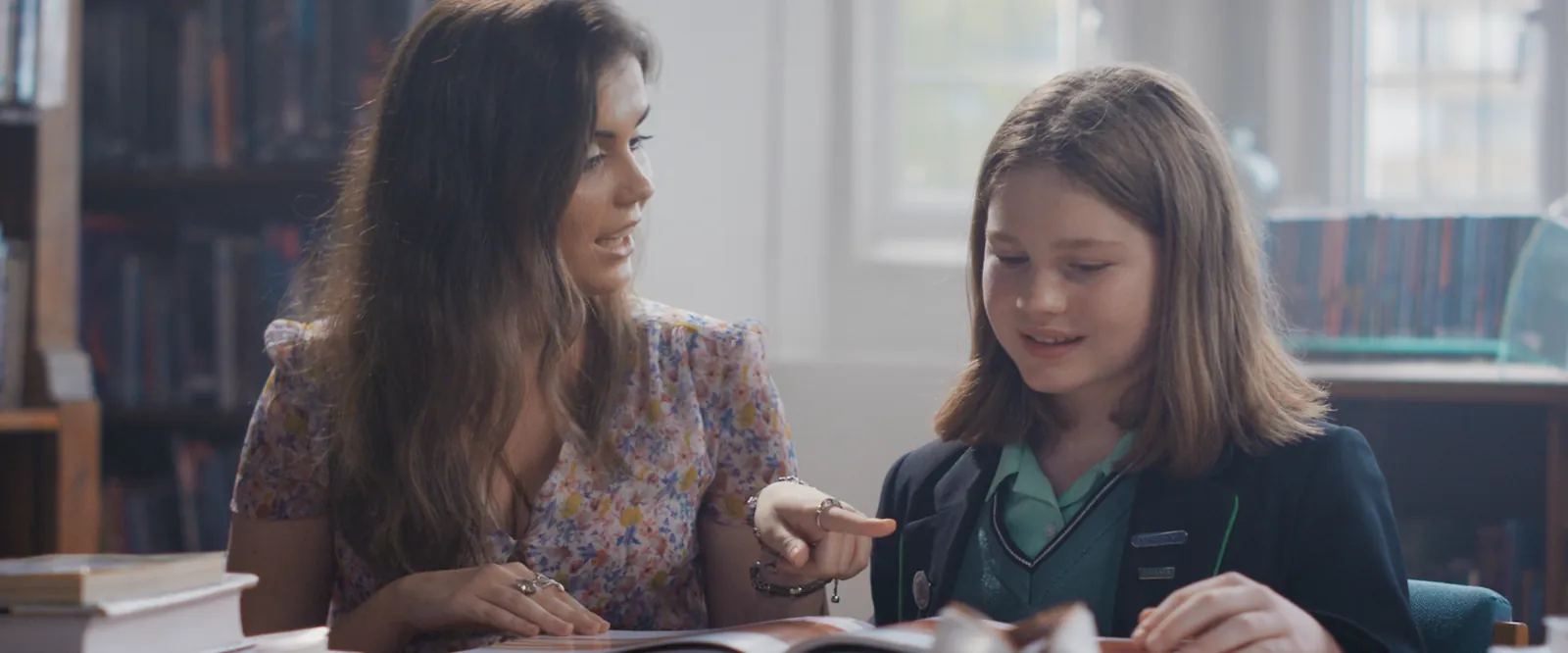 King Edward's // Brand Film still: a teacher and a pupil reading together in the library