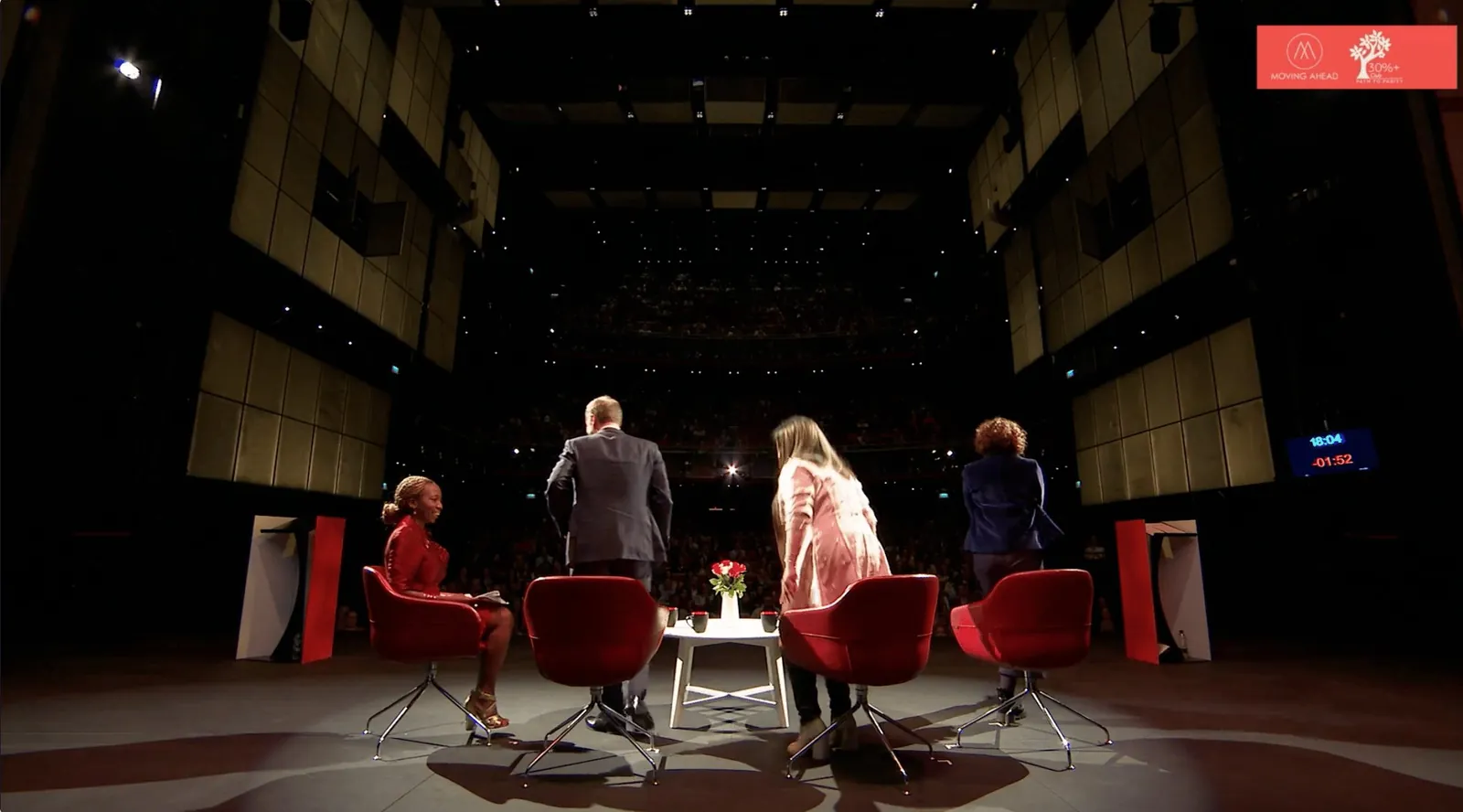 Speakers take to red chairs on stage at the Moving Ahead launch event in an auditorium at Sadler’s Wells