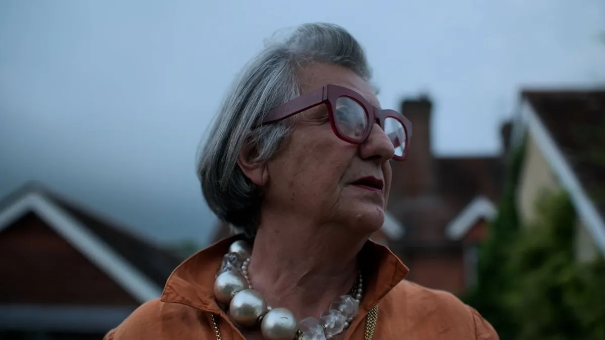 A close-up profile of a contributor wearing red-framed glasses.